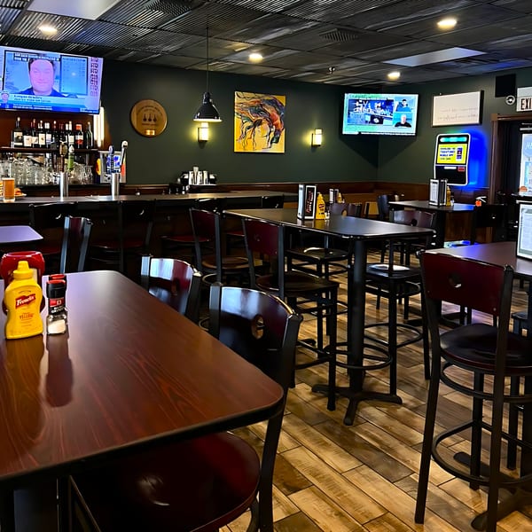 Interior of Red Creek Bar & Grill with high-top tables, bar seating, and TVs showing sports.