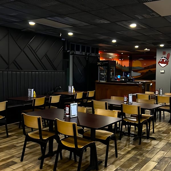 Interior of Red Creek Bar & Grill with dark tables, light wooden chairs, and a colorful mural.
