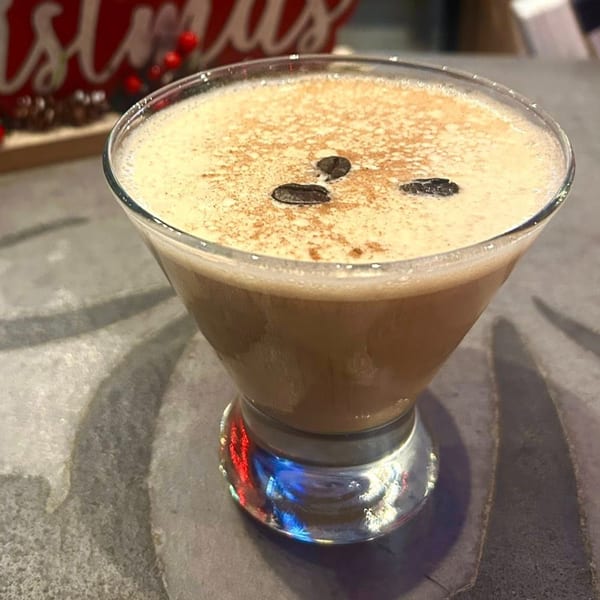Espresso martini with coffee beans and cinnamon on top, served in a martini glass.