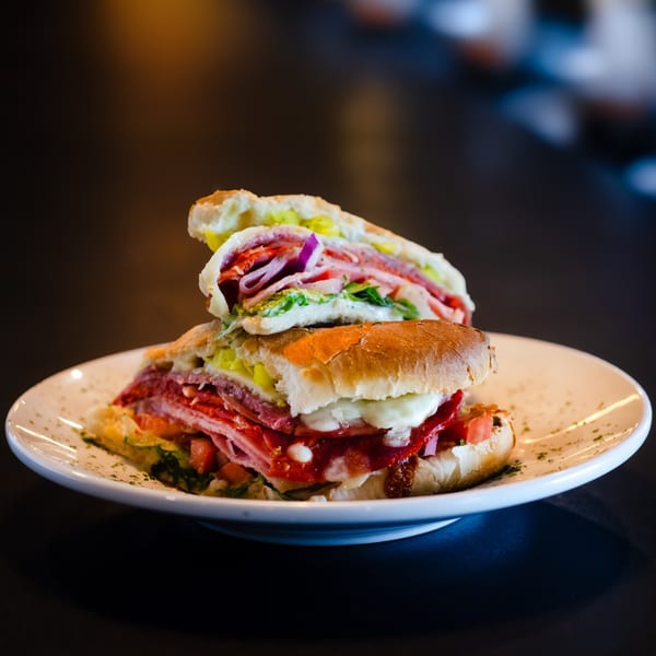 A large, sliced Red Creek Bar & Grill sandwich with meats, cheese, and vegetables on a white plate.